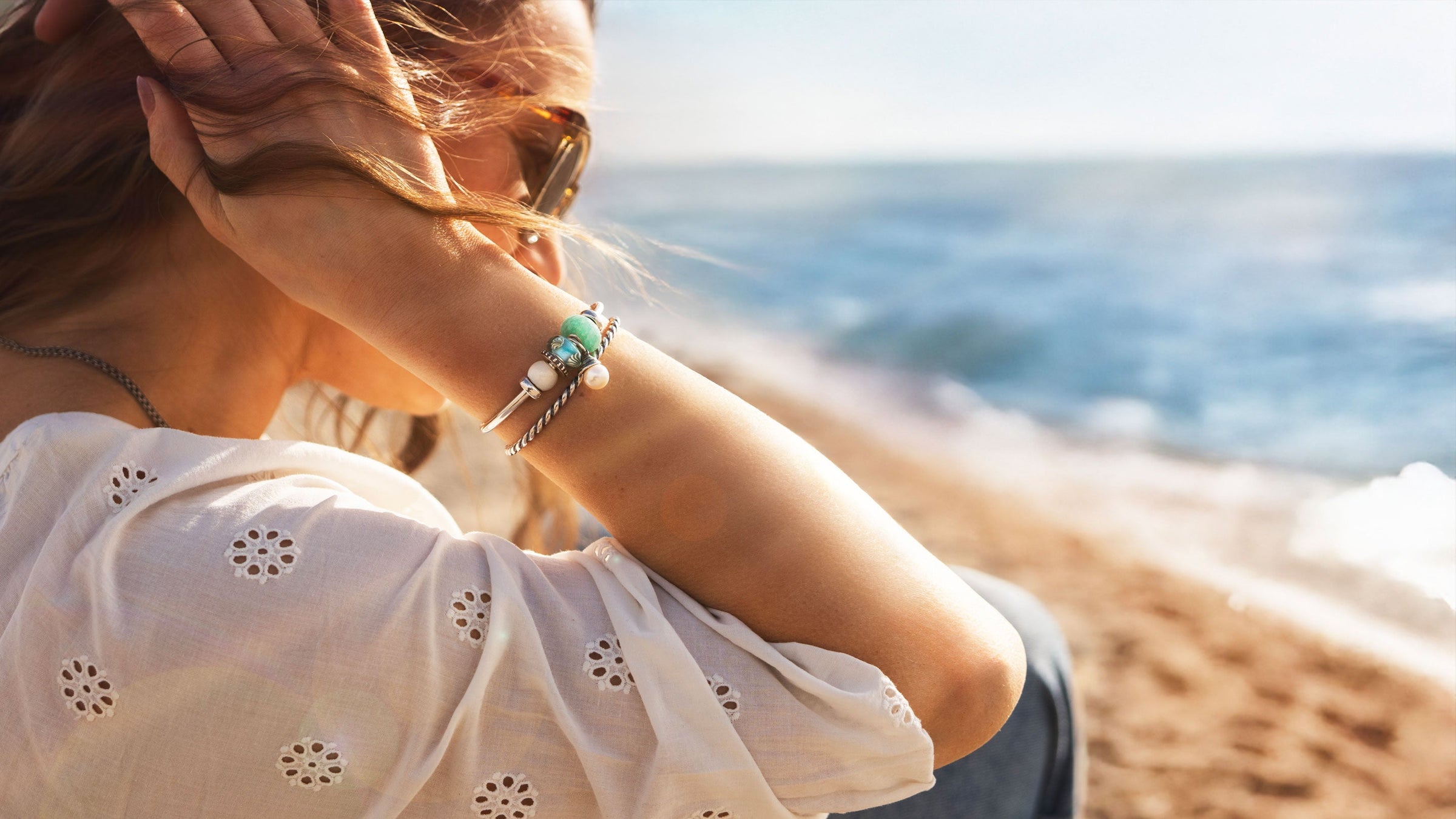 Model with silver bangles and colourful summer beads on beach, Tides of Treasure summer collection 2025